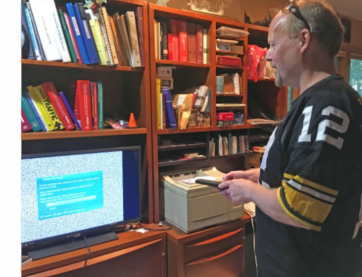 Paul is standing in front of a TV, holding a remote.